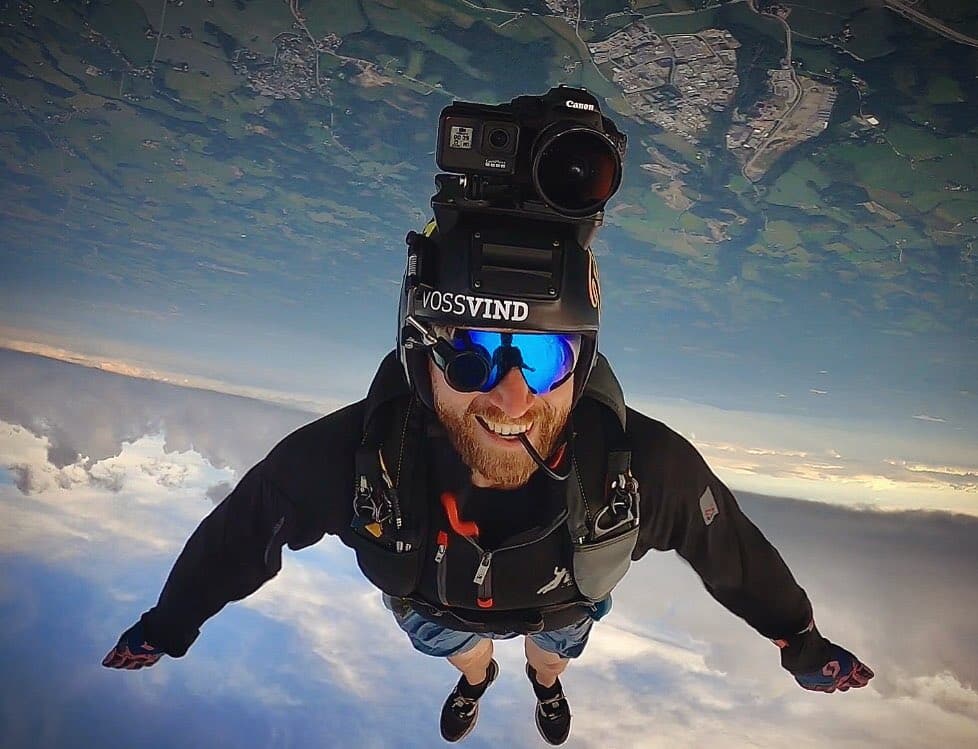 Man with a Cookie skydiving helmet and a camera on his head flying head down during freefall