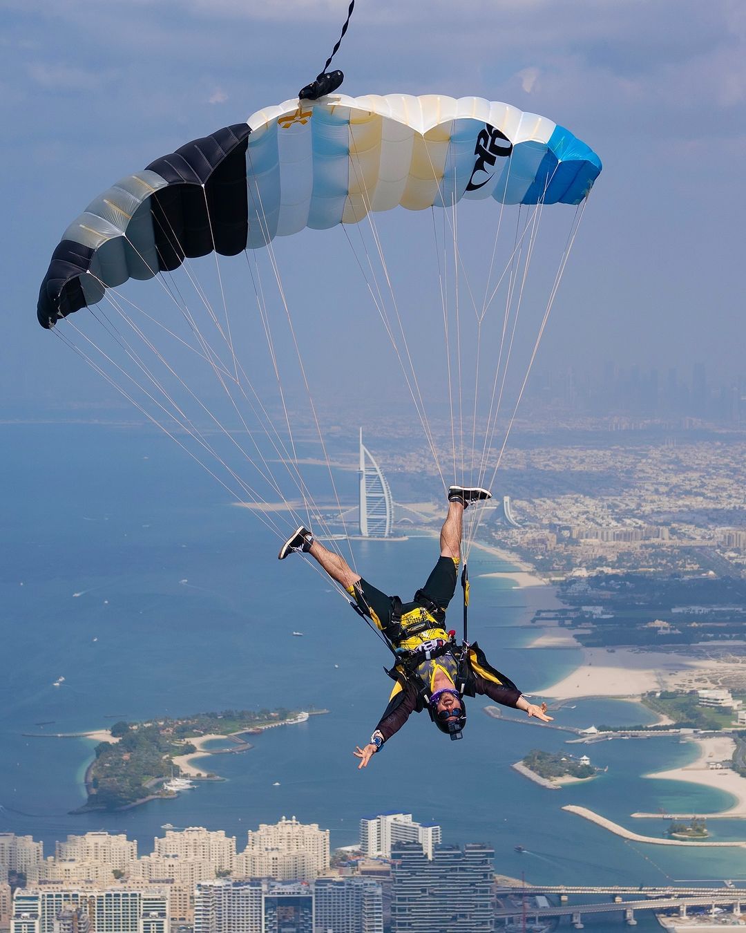 Man in black and yellow jumpsuit flying head down under canopy